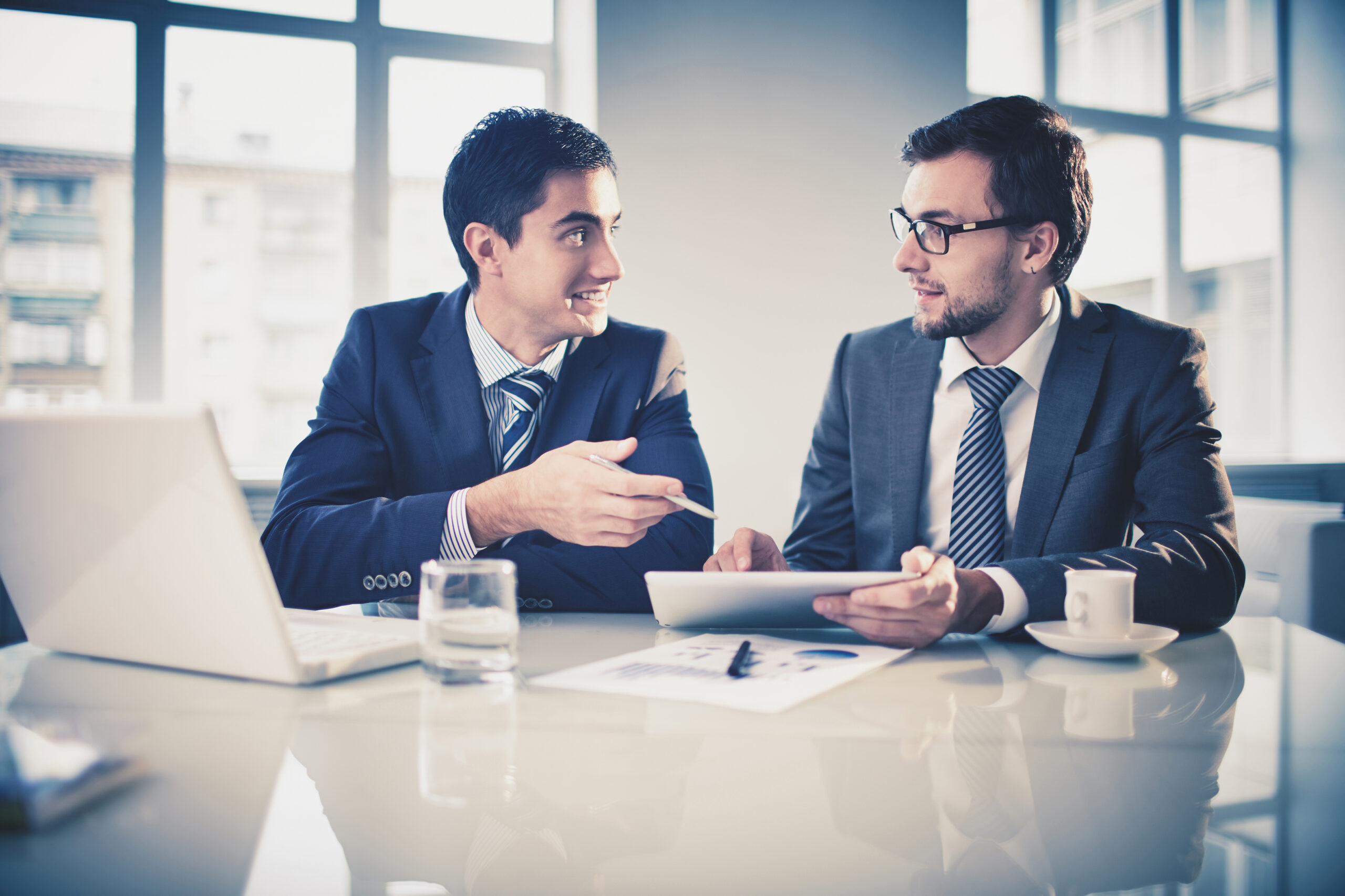 Image of two young businessmen communicating at meeting